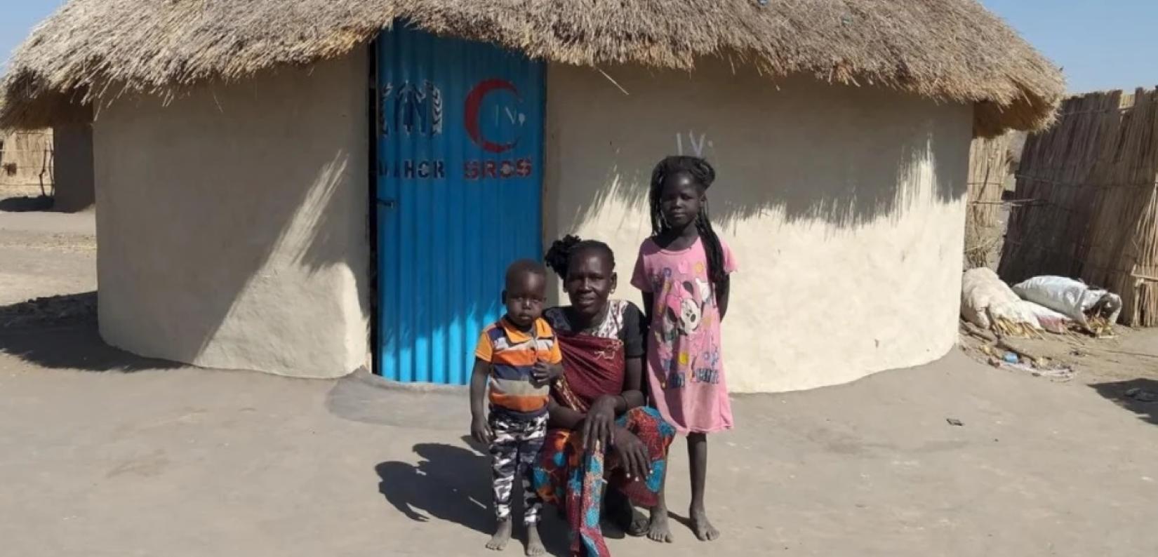 Aban, 44, with two of her children in front of their durable shelter in Al Jameya camp in White Nile State, Sudan.