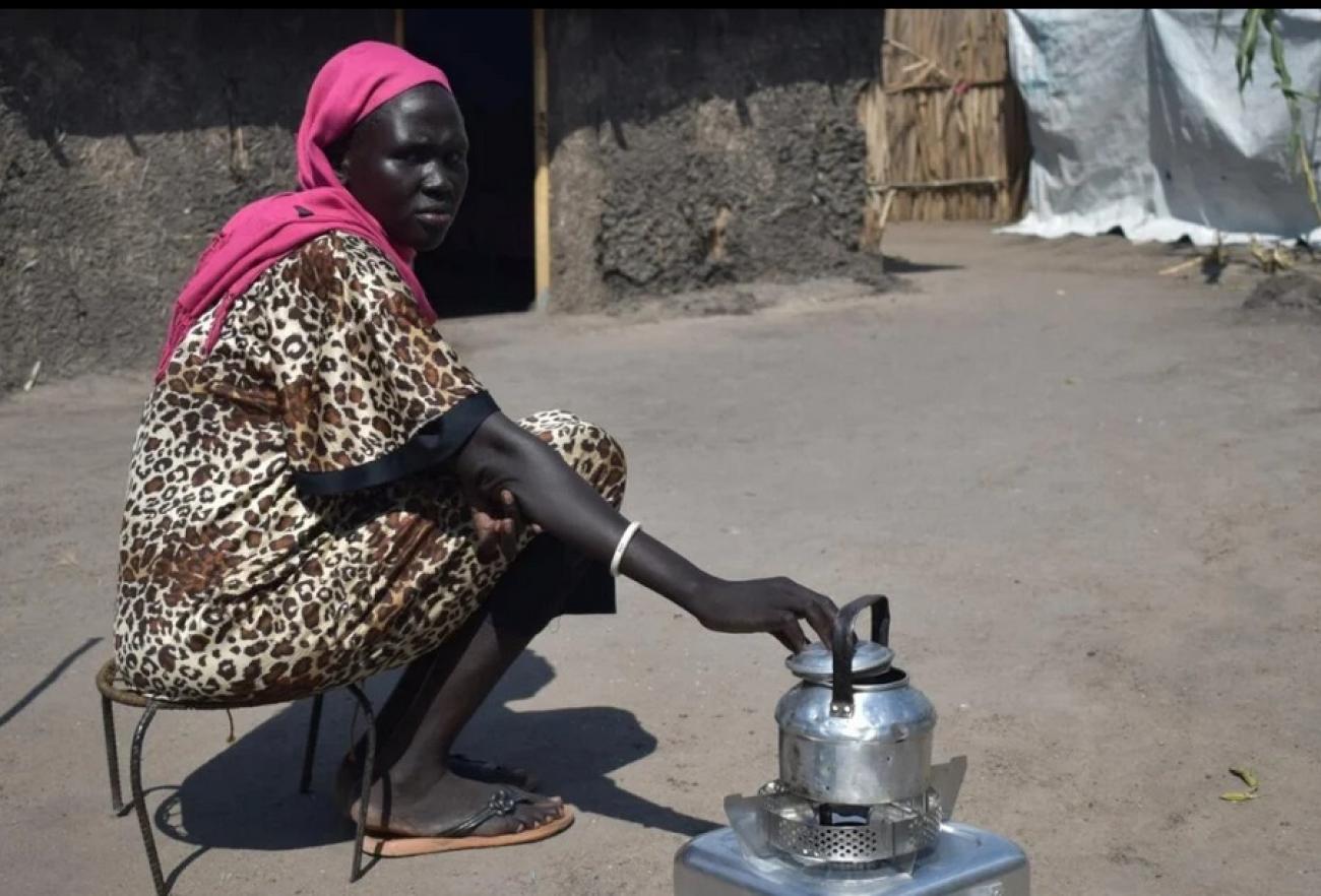 Alisa, 35, cooks on her new ethanol stove outside her compound in White Nile state, Sudan.