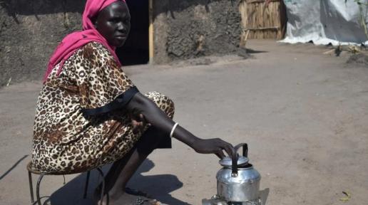 Alisa, 35, cooks on her new ethanol stove outside her compound in White Nile state, Sudan. 